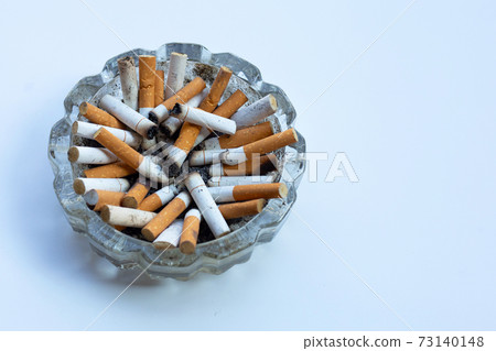 Cigarette butts in glass ashtray on white background. Cigarette butts in glass ashtray on white background. 73140148