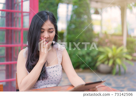 young woman sitting in the garden and using digital tablet, Education technology and internet concept. 73142506