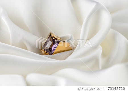 Gold ring with alexandrite on white color royalty silk fabric satin. 73142710