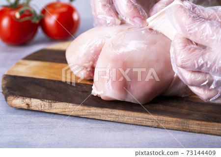 The chef removes the skin from the chicken breast to reduce the amount of fat in the food The chef removes the skin from the chicken breast to reduce the amount of fat in the food 73144409
