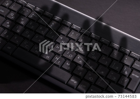 dark shadow of human hand on keyboard, cybercrime 73144583