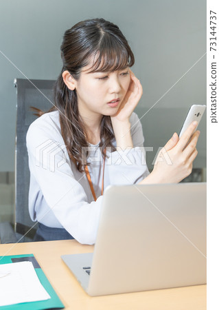 A woman who is in trouble looking at a smartphone screen A woman who is in trouble looking at a smartphone screen 73144737