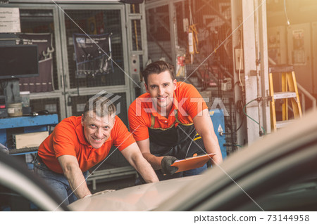 Auto mechanic worker teamwork happy working car service maintenance in garage automobile workshop 73144958