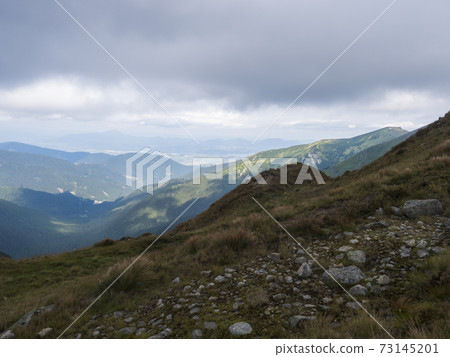 View from grassy hill slopes of hiking trail from Chopok at mountain meadow ridge Low Tatras mountains, Slovakia. Fog and clouds, late summer day View from grassy hill slopes of hiking trail from Chopok at mountain meadow ridge Low Tatras mountains, Slovakia. Fog and clouds, late summer day 73145201