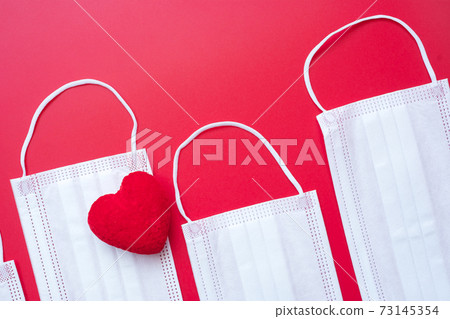 heart shape decoration and Medical face mask on red background against Coronavirus disease infection. Love, together and Happy Valentines day under Covid-19 pandemic concept heart shape decoration and Medical face mask on red background against Coronavirus disease infection. Love, together and Happy Valentines day under Covid-19 pandemic concept 73145354