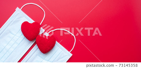 heart shape decoration and Medical face mask on red background against Coronavirus disease infection. Love, together and Happy Valentines day under Covid-19 pandemic concept heart shape decoration and Medical face mask on red background against Coronavirus disease infection. Love, together and Happy Valentines day under Covid-19 pandemic concept 73145358
