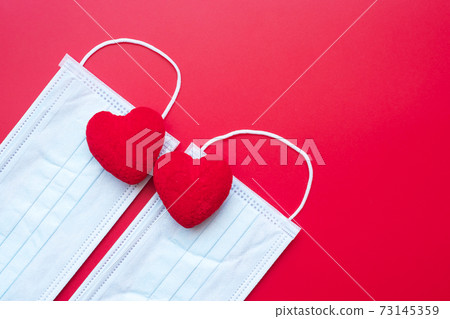 heart shape decoration and Medical face mask on red background against Coronavirus disease infection. Love, together and Happy Valentines day under Covid-19 pandemic concept heart shape decoration and Medical face mask on red background against Coronavirus disease infection. Love, together and Happy Valentines day under Covid-19 pandemic concept 73145359