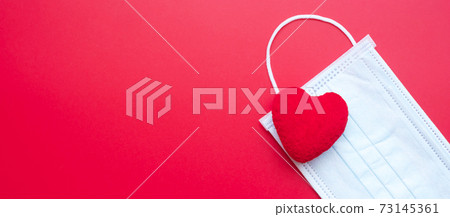 heart shape decoration and Medical face mask on red background against Coronavirus disease infection. Love, together and Happy Valentines day under Covid-19 pandemic concept heart shape decoration and Medical face mask on red background against Coronavirus disease infection. Love, together and Happy Valentines day under Covid-19 pandemic concept 73145361
