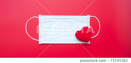 heart shape decoration and Medical face mask on red background against Coronavirus disease infection. Love, together and Happy Valentines day under Covid-19 pandemic concept heart shape decoration and Medical face mask on red background against Coronavirus disease infection. Love, together and Happy Valentines day under Covid-19 pandemic concept 73145362