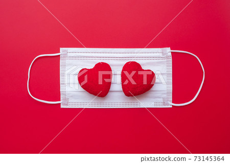 heart shape decoration and Medical face mask on red background against Coronavirus disease infection. Love, together and Happy Valentines day under Covid-19 pandemic concept heart shape decoration and Medical face mask on red background against Coronavirus disease infection. Love, together and Happy Valentines day under Covid-19 pandemic concept 73145364