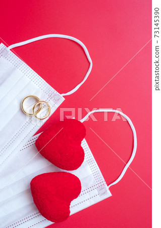 heart shape decoration, golden engagement ring and Medical face mask on red background against Coronavirus disease infection. Love, together and Happy Valentines day under Covid-19 pandemic concept heart shape decoration, golden engagement ring and Medical face mask on red background against Coronavirus disease infection. Love, together and Happy Valentines day under Covid-19 pandemic concept 73145390