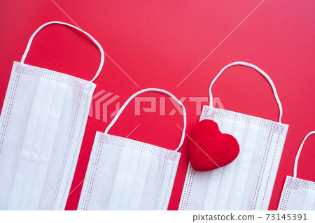 heart shape decoration and Medical face mask on red background against Coronavirus disease infection. Love, together and Happy Valentines day under Covid-19 pandemic concept heart shape decoration and Medical face mask on red background against Coronavirus disease infection. Love, together and Happy Valentines day under Covid-19 pandemic concept 73145391