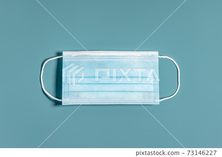 Surgical mask with rubber ear straps on blue background. 73146227