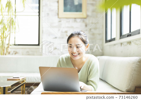 A woman who plays a personal computer in the living room 73146260