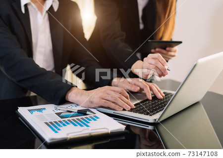Business documents on office table with smart phone and calculator digital tablet and graph business with social network diagram and two colleagues discussing data working in the office 73147108