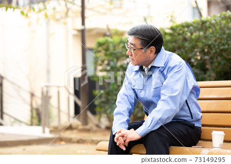 坐在公園的長椅上的工作服的男人 坐在公園的長椅上的工作服的男人 73149295