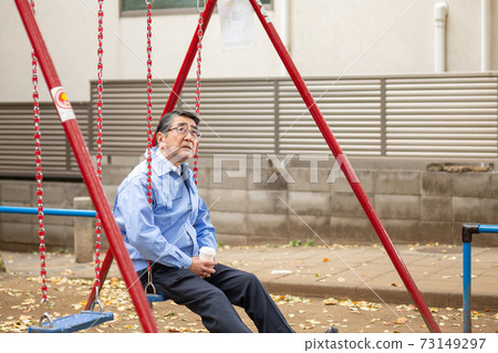 一個穿著工作服的人在公園的鞦韆上的暮光之城 一個穿著工作服的人在公園的鞦韆上的暮光之城 73149297