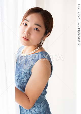 Woman in a dress standing in front of the window 73149545