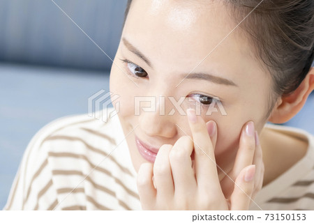 Young woman putting in contact lenses Young woman putting in contact lenses 73150153