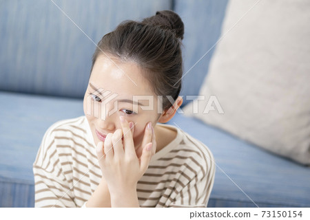 Young woman putting in contact lenses Young woman putting in contact lenses 73150154