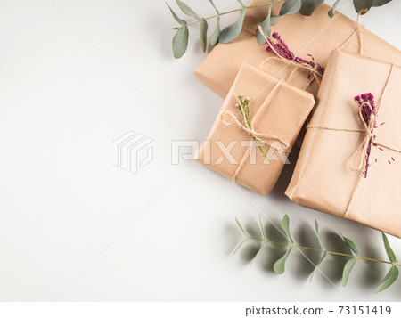 Gift box wrapped in craft paper with dried flowers 73151419