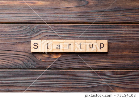 startup word written on wood block. startup text on table, concept 73154108