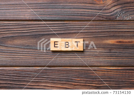 EBT word written on wood block. Abbreviation Earnings Before Taxes text on cement table for your desing, concept 73154130