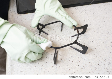 At hand of a house cleaning worker who cleans the trivet At hand of a house cleaning worker who cleans the trivet 73154304