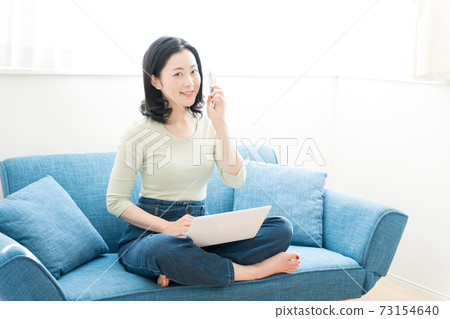 一個三十多歲的女人在沙發上操作電腦 73154640