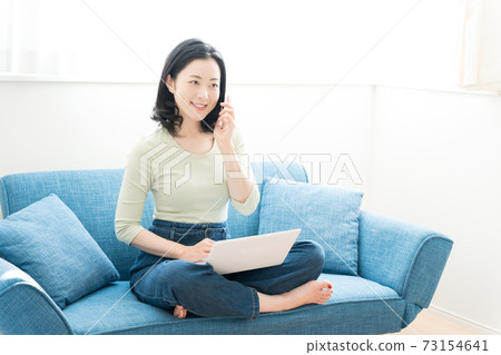 一個三十多歲的女人在沙發上操作電腦 一個三十多歲的女人在沙發上操作電腦 73154641