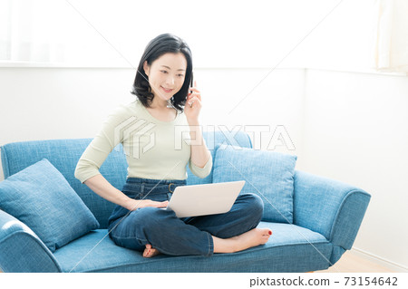 一個三十多歲的女人在沙發上操作電腦 一個三十多歲的女人在沙發上操作電腦 73154642