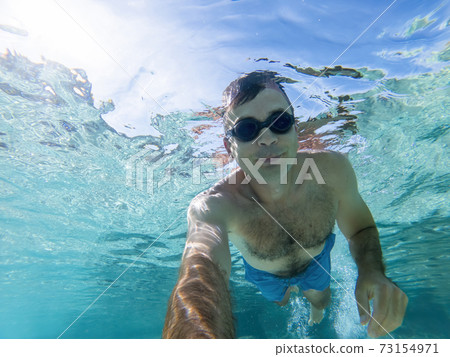 Caucasian man swimming under the water Caucasian man swimming under the water 73154971