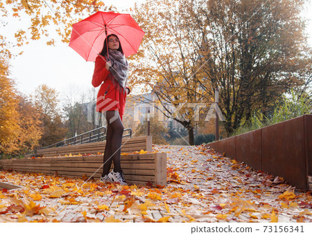 young girl in a red coat with an umbrella standing on the alley young girl in a red coat with an umbrella standing on the alley 73156341