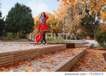 young girl in a red coat with an umbrella standing on the alley young girl in a red coat with an umbrella standing on the alley 73156372