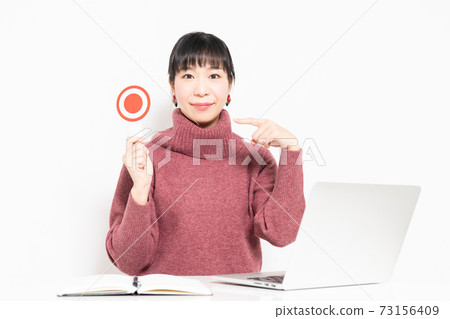 A woman holding an OK placard while using a computer 73156409