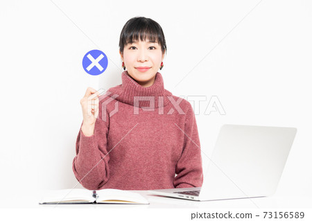 A woman holding an NG placard while using a laptop A woman holding an NG placard while using a laptop 73156589