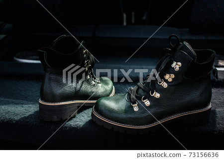 High women's or unisex shoes. Pair of boots with shoe laces. Modern youth fashion of women's casual footwear. Dark green glossy leather shoes. 73156636