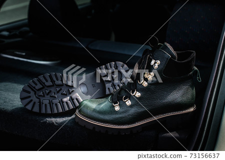 High women's or unisex shoes. Pair of boots with shoe laces. Modern youth fashion of women's casual footwear. Dark green glossy leather shoes. 73156637