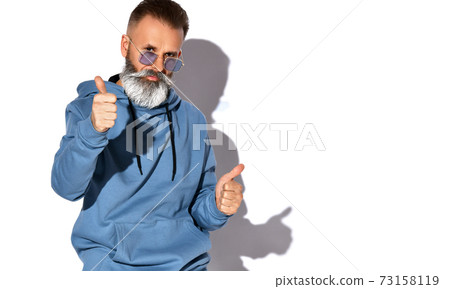 Stylish man with a gray beard and mustache stands 73158119