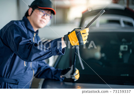 Asian auto mechanic checking windshield wiper Asian auto mechanic checking windshield wiper 73159337