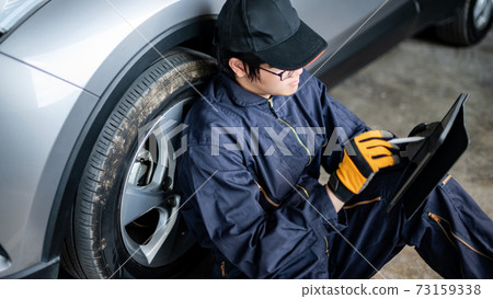 Asian auto mechanic checking the car wheel using tablet Asian auto mechanic checking the car wheel using tablet 73159338