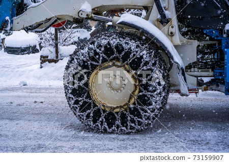 Closeup of a chained wheel of a snowy snow plow . Closeup of a chained wheel of a snowy snow plow . 73159907