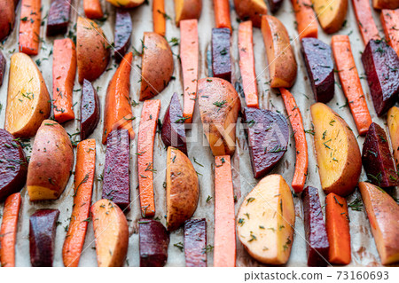 restaurant, vegetarianism, fast, healthy food, recipes concepts - raw cut potatoes carrots, beets with seasoning dill. fresh marinated vegetables in jackets on paper. Top view. Close up before cooking 73160693