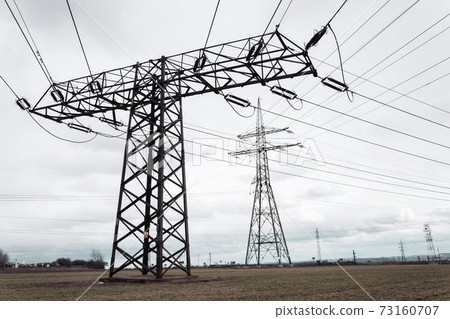 Electricity pylons conducting current from distribution power station, solar renewable energy and grid stability concept, copy space dramatic clouds Electricity pylons conducting current from distribution power station, solar renewable energy and grid stability concept, copy space dramatic clouds 73160707