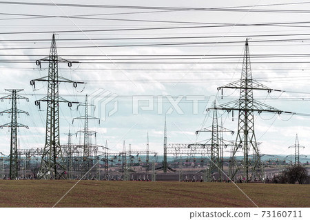 Electricity pylons conducting current from distribution power station, solar renewable energy and grid stability concept, copy space dramatic clouds Electricity pylons conducting current from distribution power station, solar renewable energy and grid stability concept, copy space dramatic clouds 73160711