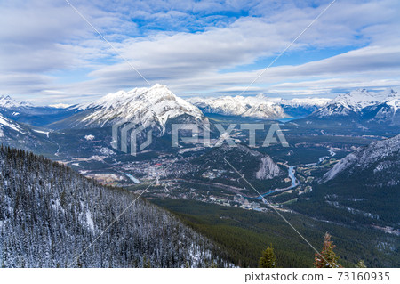 Overlook view Town of Banff, Cascade Mountain and surrounding snow-covered Canadian Rocky Mountains in early winter time. Banff National Park, Alberta, Canada. 73160935