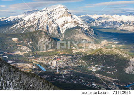 Overlook view Town of Banff, Cascade Mountain and surrounding snow-covered Canadian Rocky Mountains in early winter time. Banff National Park, Alberta, Canada. 73160936