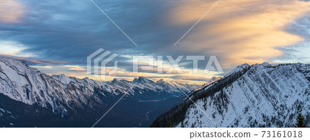 Snow capped Mount Rundle mountain range in beautiful dusk. Sky of red pink clouds in the background. Banff National Park in winter, Canadian Rockies. Beautiful nature scenery. 73161018