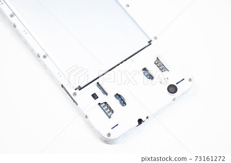 A cell phone with an open cover lies face down on a white background. A cell phone with an open cover lies face down on a white background. 73161272