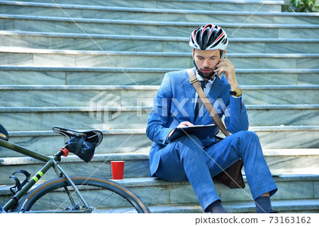 Businessman  sitting on stairs analyzes report 73163162